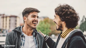 Two young men laughing joyfully while talking outdoors, demonstrating the positive outcome of using lighthearted Conversation Starters.