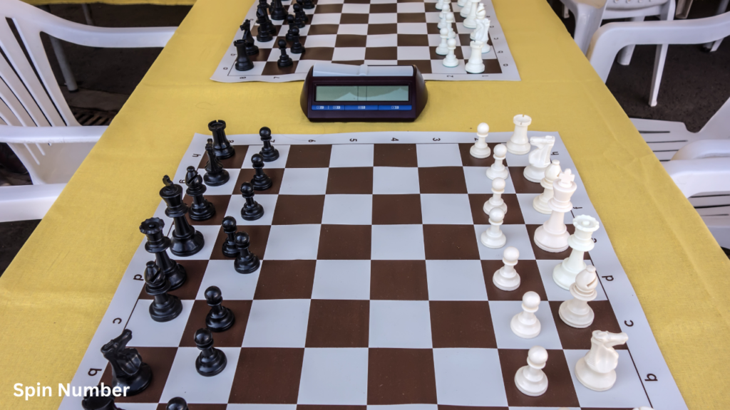 Two chessboards fully set up with black and white pieces on a yellow table with a central digital match timer, ready for the next round of a Tournament Bracket.