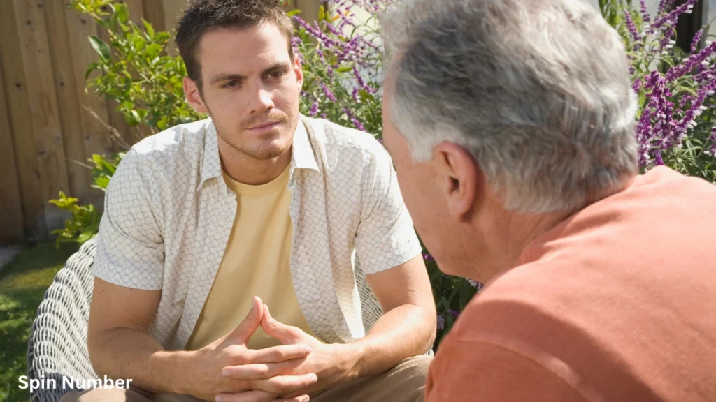 A serious young man listening intently during a deep conversation in an outdoor garden, demonstrating the mood for meaningful Questions to Ask Your Crush.