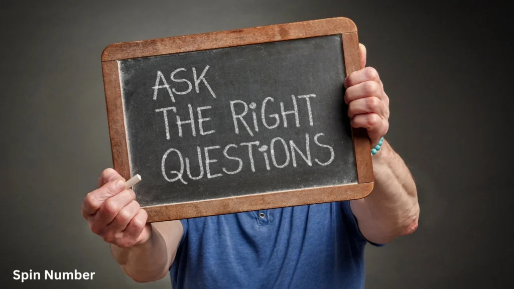 A person holding up a vintage handheld slate chalkboard that reads "ASK THE RIGHT QUESTIONS" in white chalk, perfect for brainstormed Questions to Ask Your Crush.