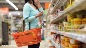 A woman carrying a shopping basket stands thoughtfully in front of crowded supermarket shelves, experiencing the paradox of choice while shopping.