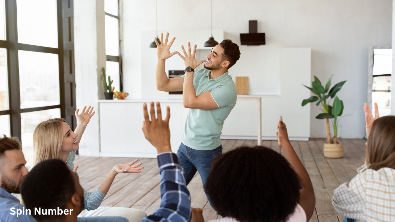 A group of happy friends gathered in a bright living room laughing and guessing as a man acts out funny Charades Ideas.
