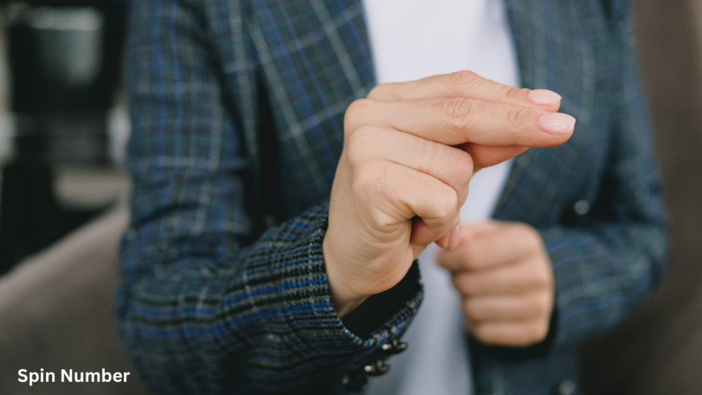 Close-up of a person in a plaid blazer gesturing a small pinch sign with their fingers while acting out Charades Ideas.