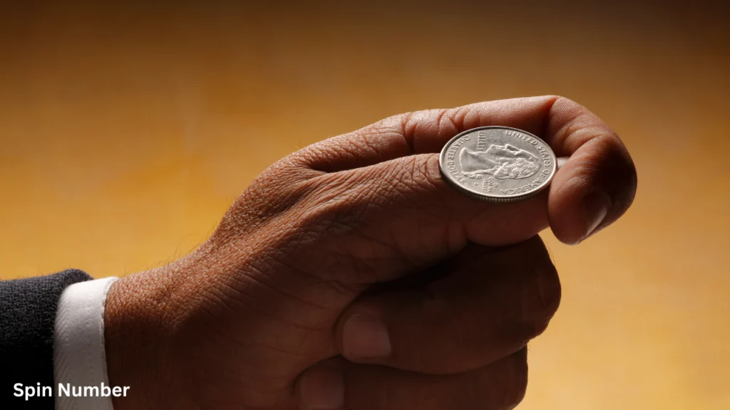 A close-up of a hand preparing to Flip a Coin using a silver United States quarter dollar balanced on the thumb.