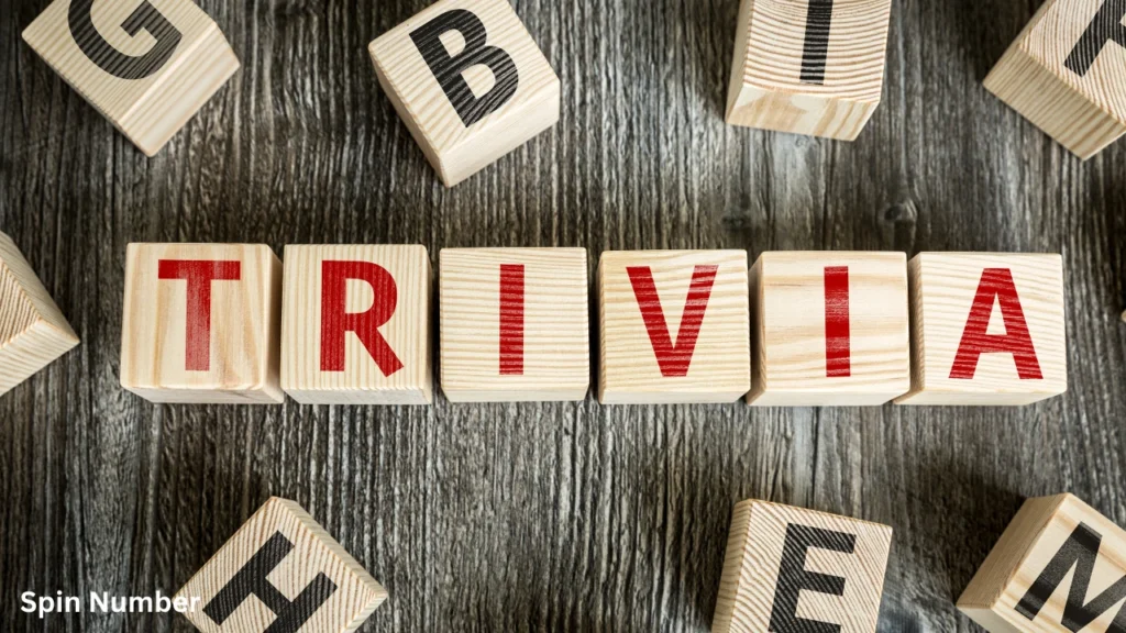 Wooden toy letter blocks arranged on a grey wood grain background to spell out "TRIVIA", perfect for a fun night of Trivia Questions.