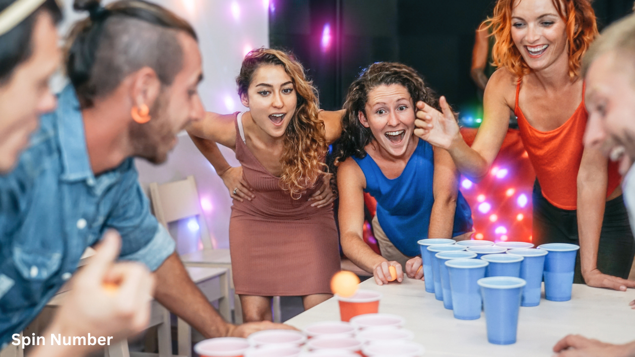 An excited crowd cheering during a lively game of beer pong at a indoor night event, highlighting classic drinking-style Party Games for Adults.