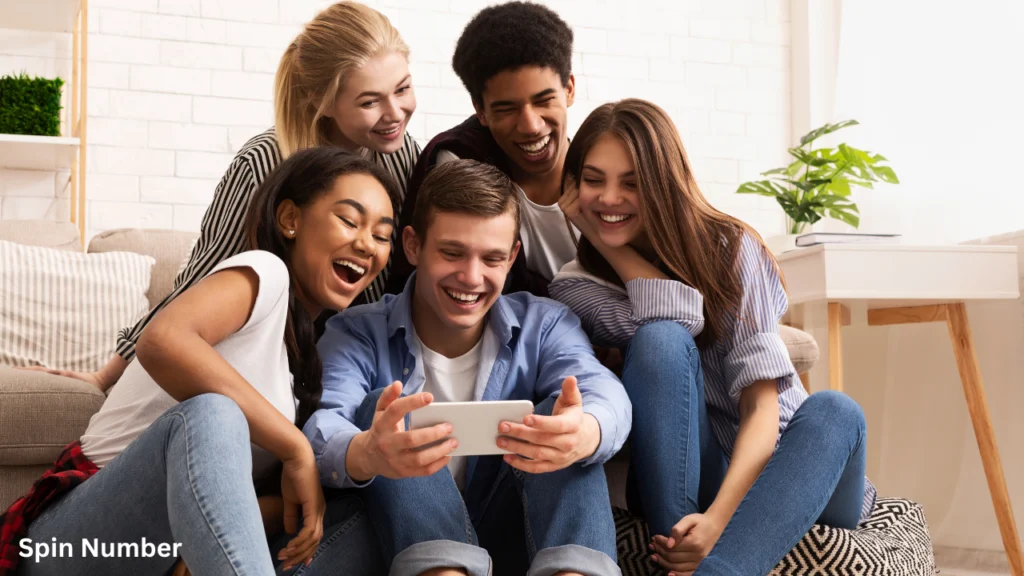 A group of five excited friends laughing together while looking at a smartphone screen, enjoying interactive online Spin the Wheel Games.