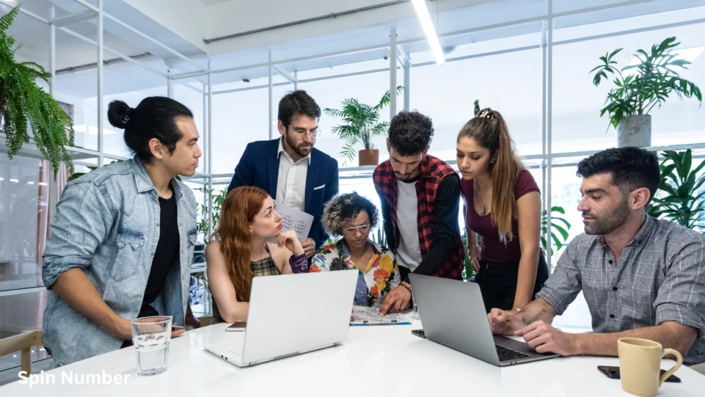 A professional office team collaborating around laptops, using corporate-friendly Two Truths and a Lie Ideas for a team-building session.