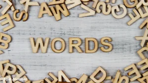 Wooden alphabet letters scattered on a rustic white table surrounding the central word "WORDS", ideal for selecting challenging Hangman Words.